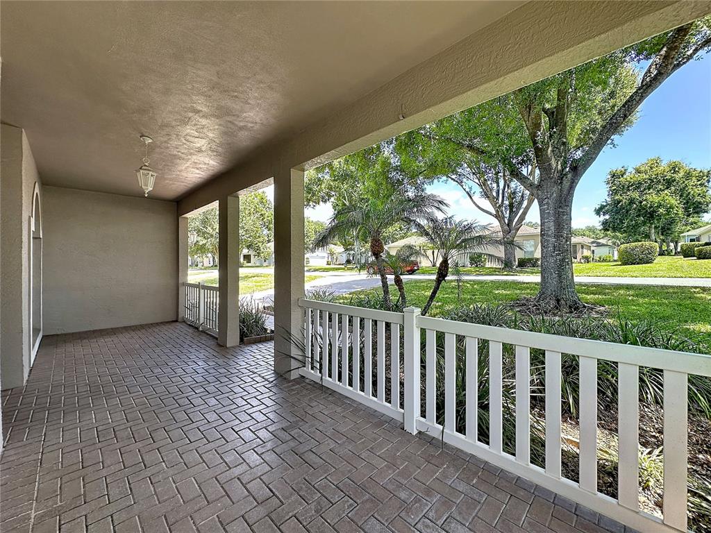 A covered brick patio features a white railing overlooking a grassy yard with trees — 4223 KINGSLEY STREET, CLERMONT, FL