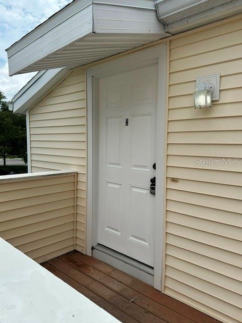 A white door labeled H is set into the light yellow vinyl siding of a building — 130 SABAL COURT UNIT H, OLDSMAR, FL