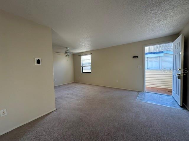 An empty carpeted living room features a ceiling fan, a window, and an open door — 130 SABAL COURT UNIT H, OLDSMAR, FL