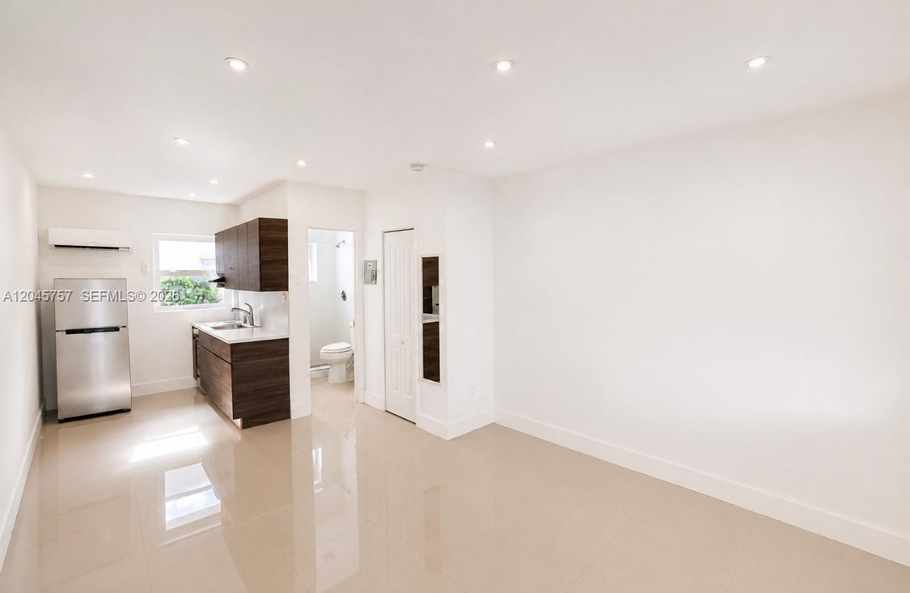 A small kitchen area features dark wood cabinets, stainless steel appliances, and light tile flooring — 551 NE 61st St # 4, Miami FL 33137, MIAMI, FL