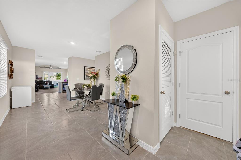 A tiled entryway leads to a dining area with a mirrored console table and mirror — 2900 WATERLILY WAY, POINCIANA, FL