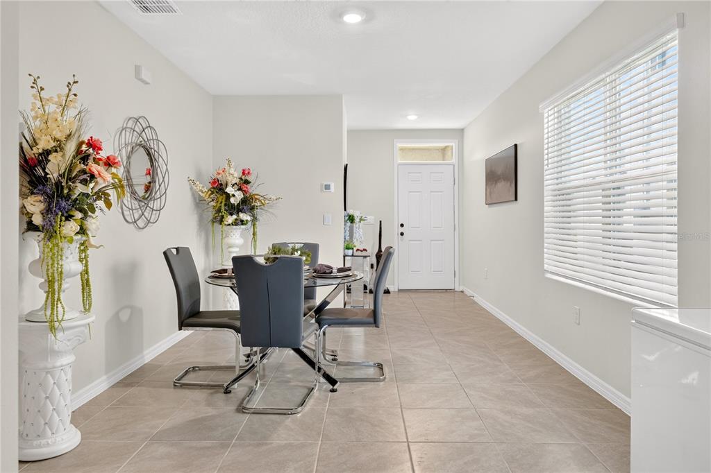 A dining area features tile flooring, a glass-top table with four chairs, and a front door — 2900 WATERLILY WAY, POINCIANA, FL