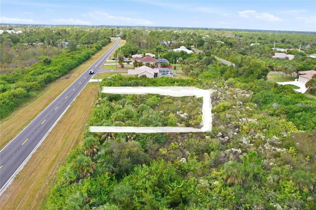 An aerial view shows a rectangular vacant lot outlined in white next to a road — 9424 WILLMINGTON BOULEVARD, ENGLEWOOD, FL