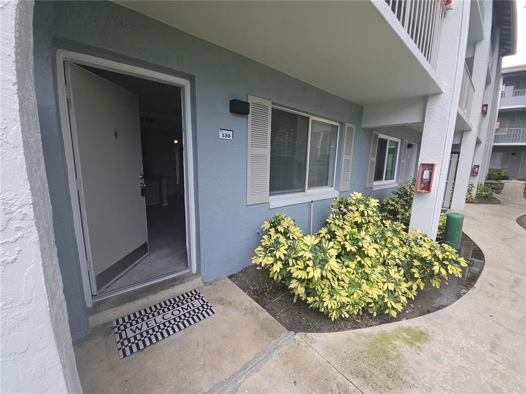 The exterior view shows the entrance to a ground-floor apartment unit with a welcome mat — 125 WATER FRONT WAY UNIT 130, ALTAMONTE SPRINGS, FL