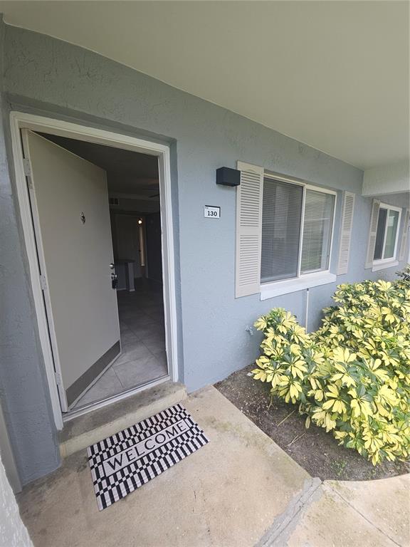 An exterior view of a ground-level apartment entrance with a welcome mat and landscaping — 125 WATER FRONT WAY UNIT 130, ALTAMONTE SPRINGS, FL