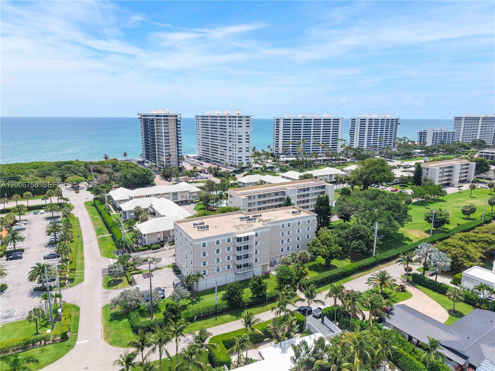 An aerial view shows a multi-story apartment building surrounded by palm trees and parking lots — 950 De Soto Rd # 3C, Boca Raton FL 33432, BOCA RATON, FL