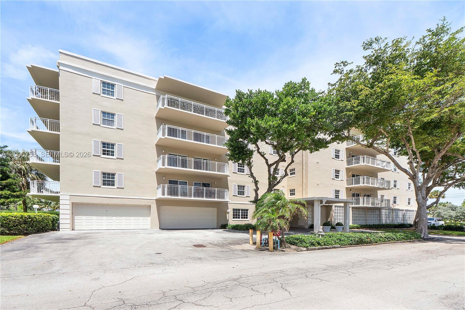A balcony with a small table and two chairs overlooks a parking lot and trees — 950 De Soto Rd # 3C, Boca Raton FL 33432, BOCA RATON, FL