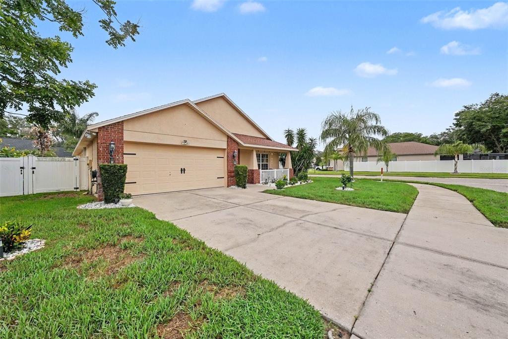 A single-story house with a tan stucco exterior, brick accents, and a two-car garage — 12337 ROSE HAVEN BOULEVARD, NEW PORT RICHEY, FL