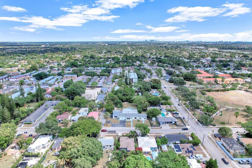 An aerial view shows a suburban neighborhood with houses, trees, and streets under a cloudy sky — 2415 Pierce St, Hollywood FL 33020, HOLLYWOOD, FL