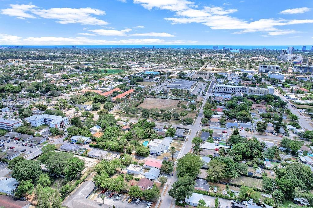 An aerial view shows a suburban neighborhood with houses, trees, and distant city buildings — 2415 Pierce St, Hollywood FL 33020, HOLLYWOOD, FL