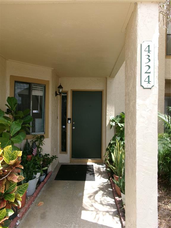 A covered entryway features a dark front door, potted plants, and a vertical address sign — 4324 MIDDLEBROOK ROAD UNIT 4324, ORLANDO, FL