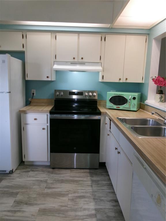 A kitchen with white cabinets, a stainless steel stove, light wood countertops, and turquoise walls — 4324 MIDDLEBROOK ROAD UNIT 4324, ORLANDO, FL