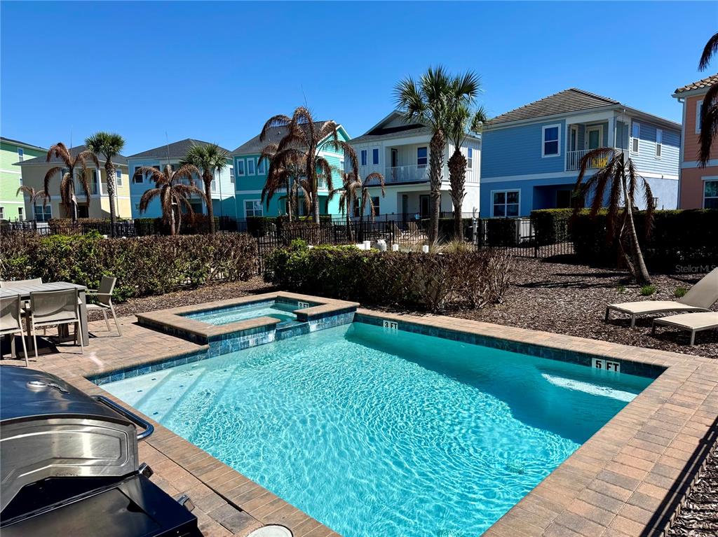 A backyard swimming pool and hot tub are surrounded by a patio and residential houses — 8031 KNEE DEEP ROAD, KISSIMMEE, FL