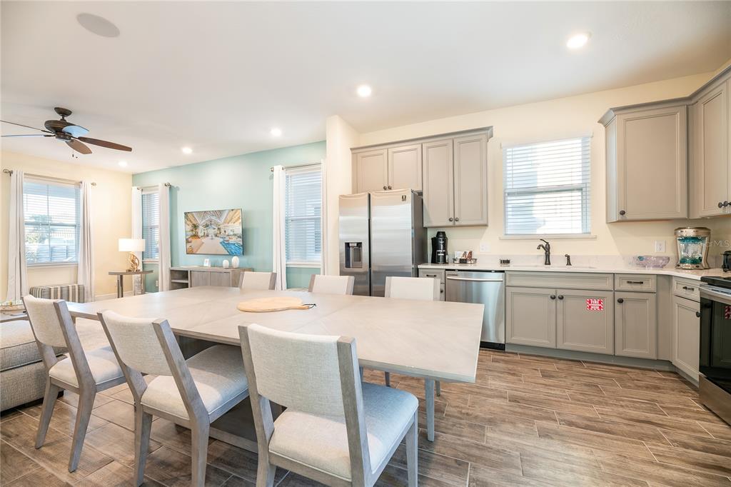 A kitchen and dining area featuring light gray cabinets, stainless steel appliances, and wood-look flooring — 8031 KNEE DEEP ROAD, KISSIMMEE, FL