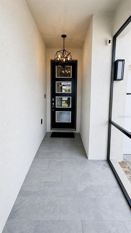 A covered entryway features a dark front door with glass panels and a globe chandelier — 4362 SOUTHERN VISTA LOOP, ST CLOUD, FL