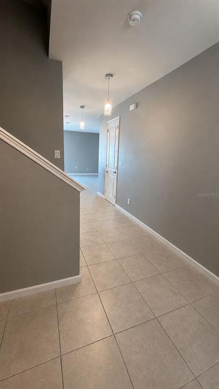 A hallway with tile flooring, gray walls, and a white door leads to an open room — 4362 SOUTHERN VISTA LOOP, ST CLOUD, FL