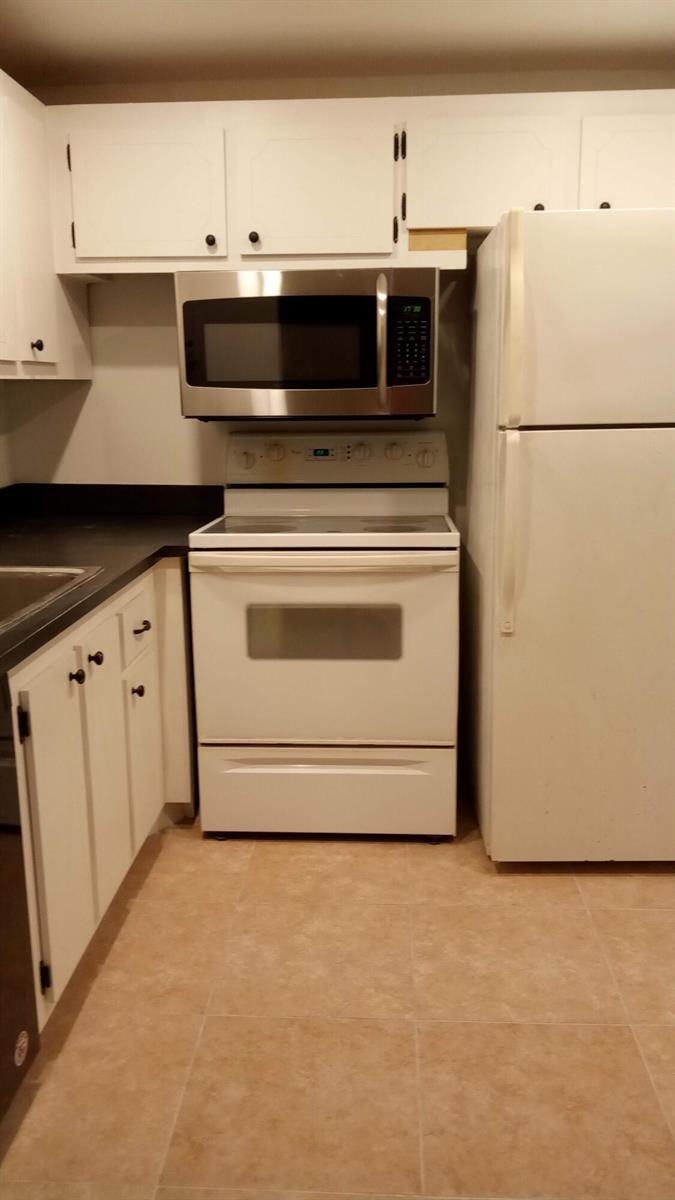 A kitchen features white cabinets, a stainless steel microwave, a white stove, and a refrigerator — 16 Dorset A, Boca Raton FL 33434, BOCA RATON, FL
