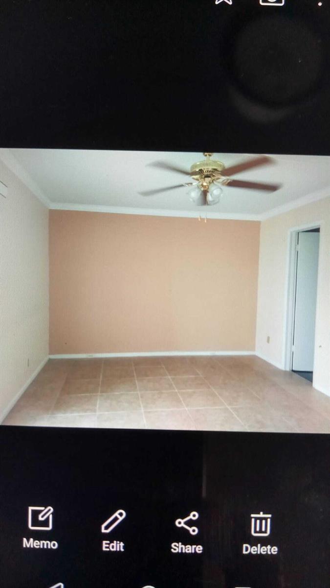 An empty room features a peach-colored accent wall, tile flooring, and a ceiling fan — 16 Dorset A, Boca Raton FL 33434, BOCA RATON, FL