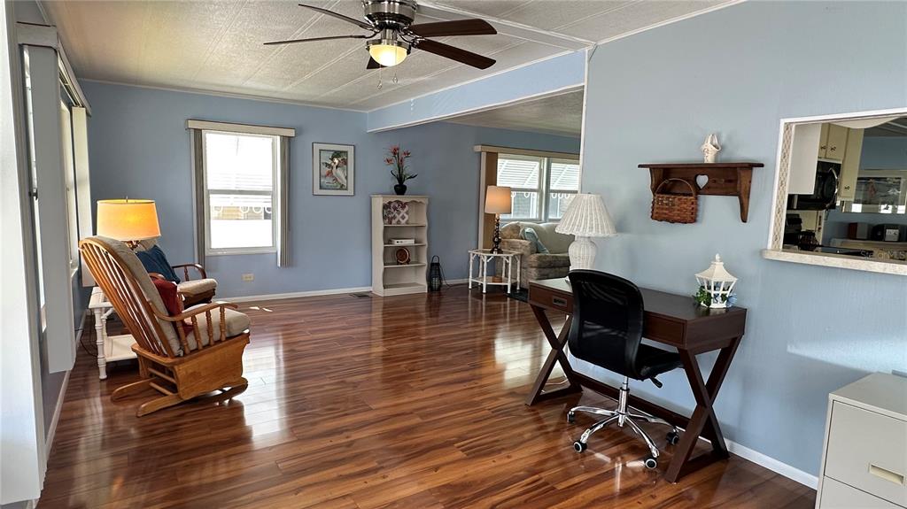A living room with wood-look flooring, a ceiling fan, a desk, and a rocking chair — 5619 BAYSHORE ROAD UNIT 163, PALMETTO, FL