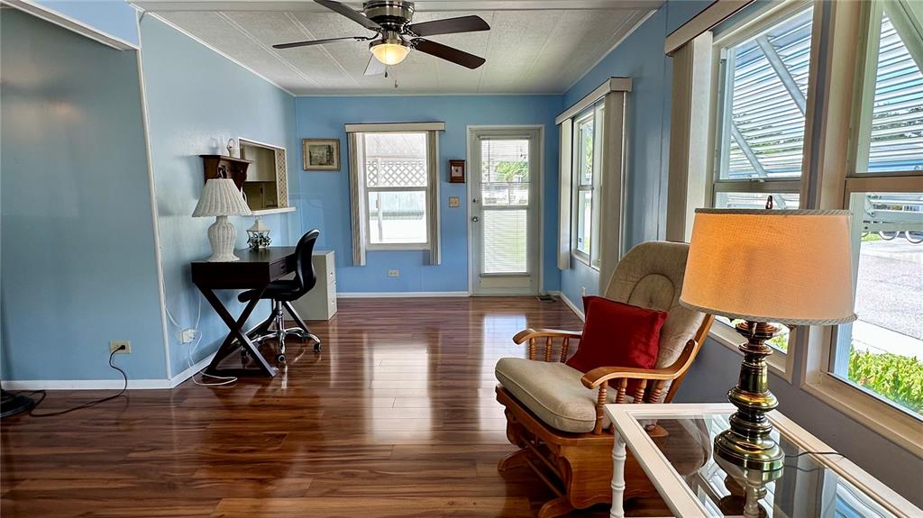 A sunroom features light blue walls, wood-look flooring, a desk, and a rocking chair — 5619 BAYSHORE ROAD UNIT 163, PALMETTO, FL