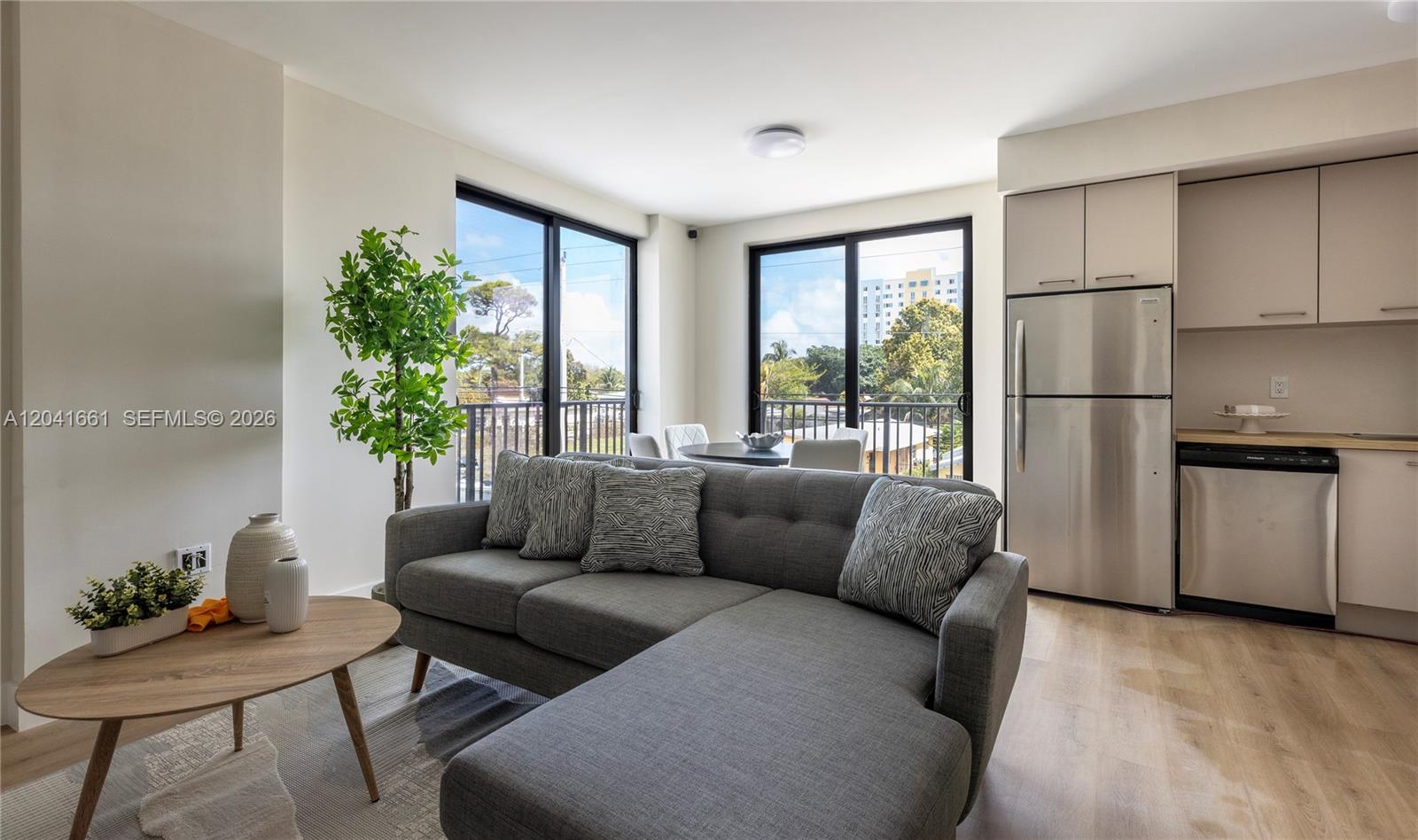 A living room with a gray sectional sofa, coffee table, and an adjacent kitchen area — 37xx NW 23 Ave # 1, Miami FL 33142, MIAMI, FL