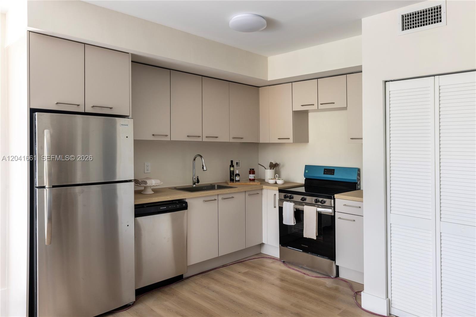This kitchen features stainless steel appliances, light-colored cabinetry, and wood-look flooring — 37xx NW 23 Ave # 1, Miami FL 33142, MIAMI, FL