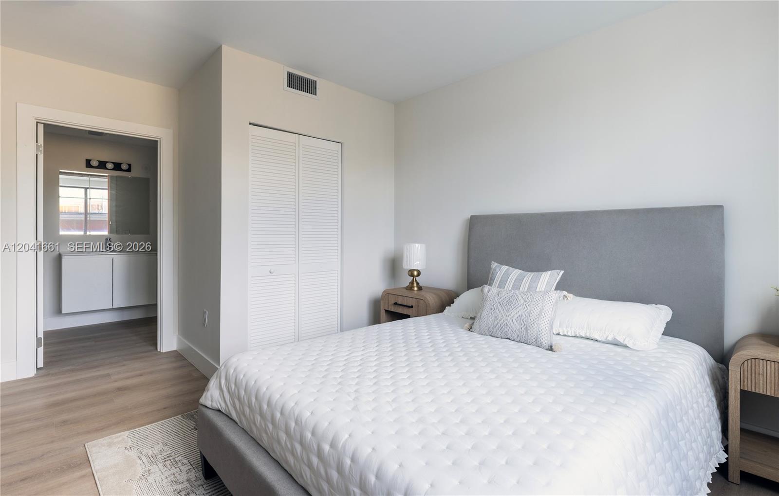 A bedroom features a gray upholstered headboard, white bedding, and an adjacent bathroom — 37xx NW 23 Ave # 1, Miami FL 33142, MIAMI, FL