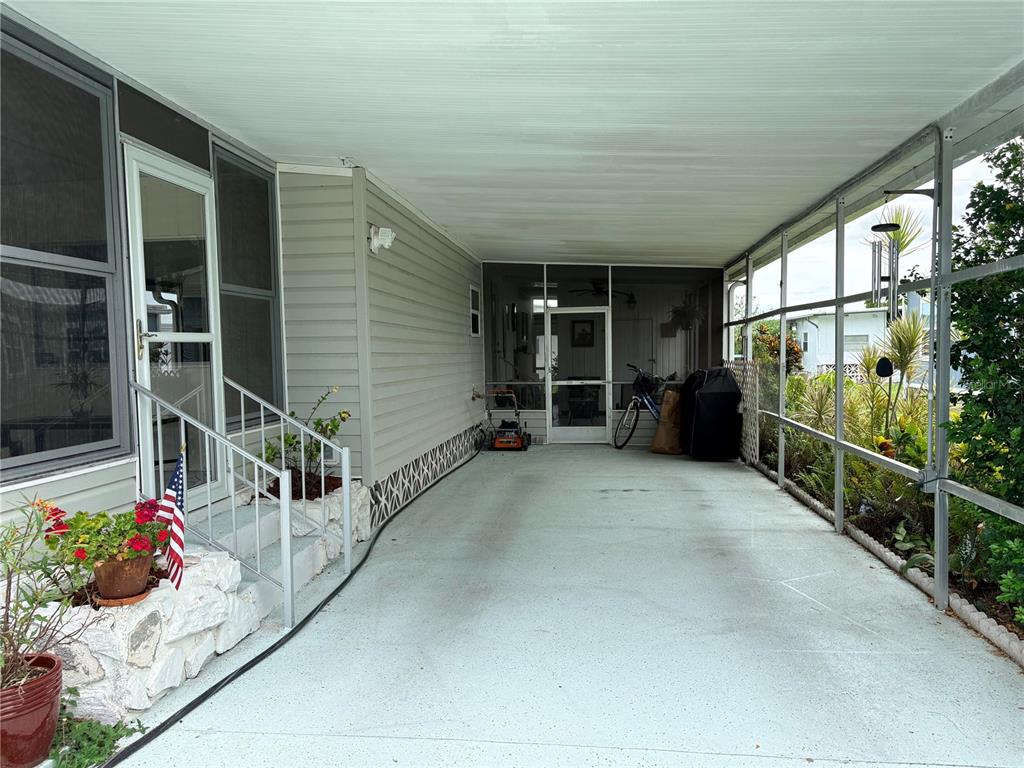A covered carport with a concrete floor leads to a screened-in porch and home entrance — 2777 INDIANWOOD DRIVE, NORTH FORT MYERS, FL