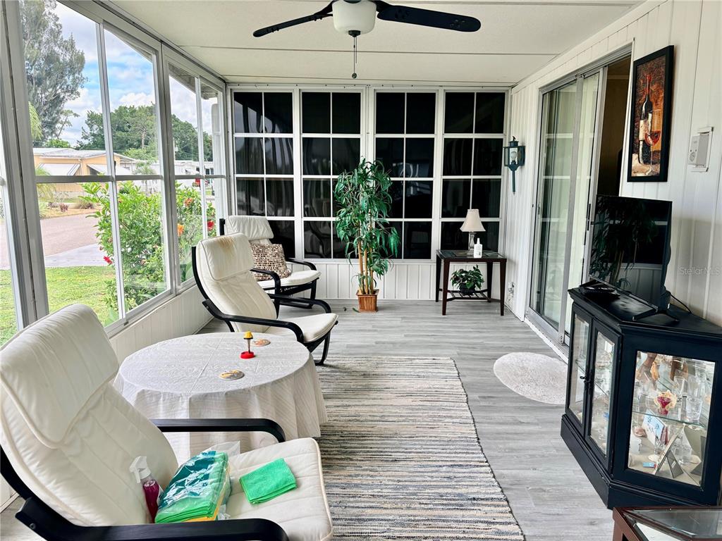 A sunroom features a ceiling fan, white chairs, a round table, and a glass-front cabinet — 2777 INDIANWOOD DRIVE, NORTH FORT MYERS, FL