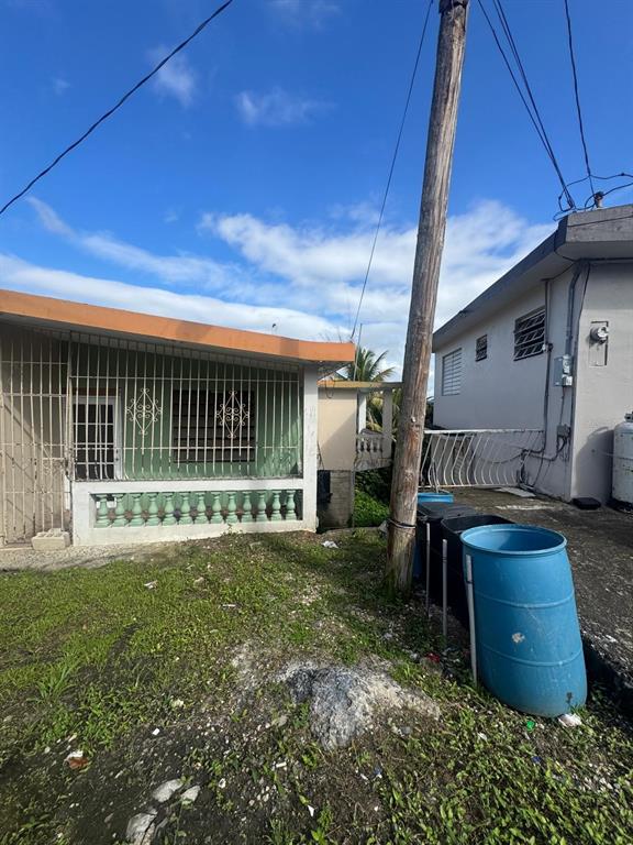 An exterior view of a house with a green porch, security bars, and a blue barrel — 487 EXT. VILLA DEL RIO, TOA ALTA, PR