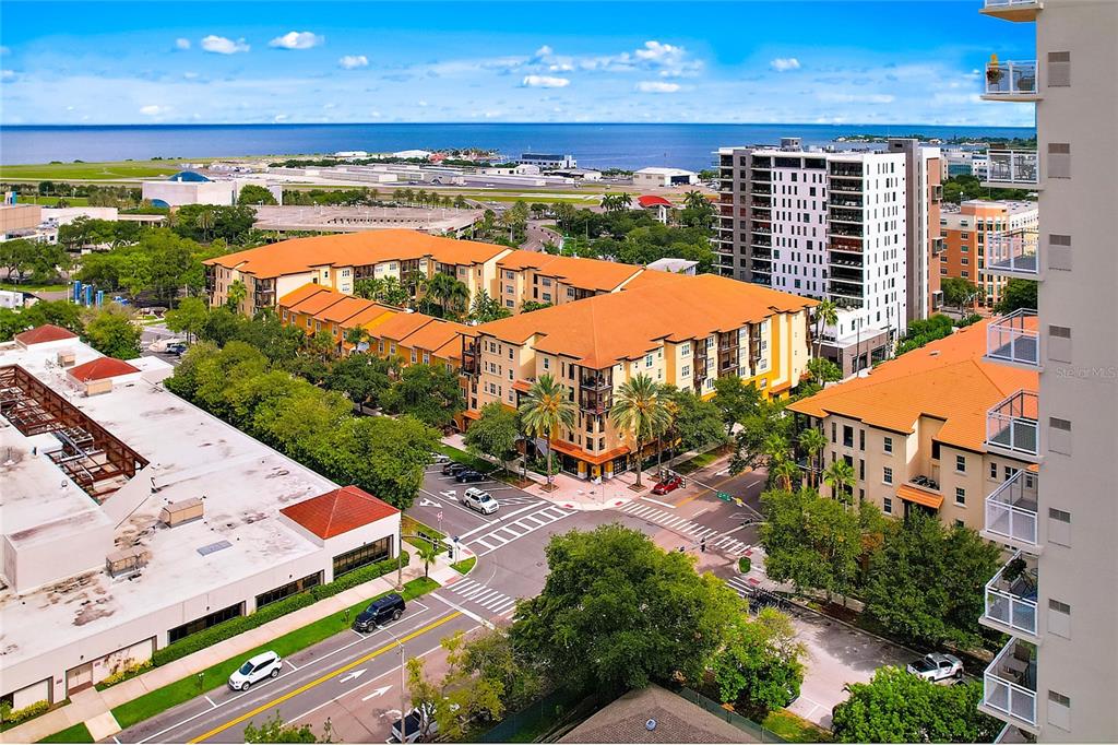 An aerial view shows a multi-story apartment complex with orange roofs near a coastal airport — 100 4TH AVENUE S UNIT 416, ST PETERSBURG, FL
