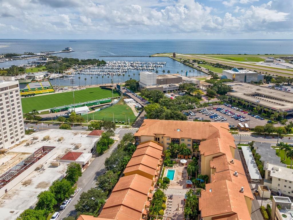 An aerial view shows a hotel complex with a pool, nearby marina, and sports field — 100 4TH AVENUE S UNIT 416, ST PETERSBURG, FL
