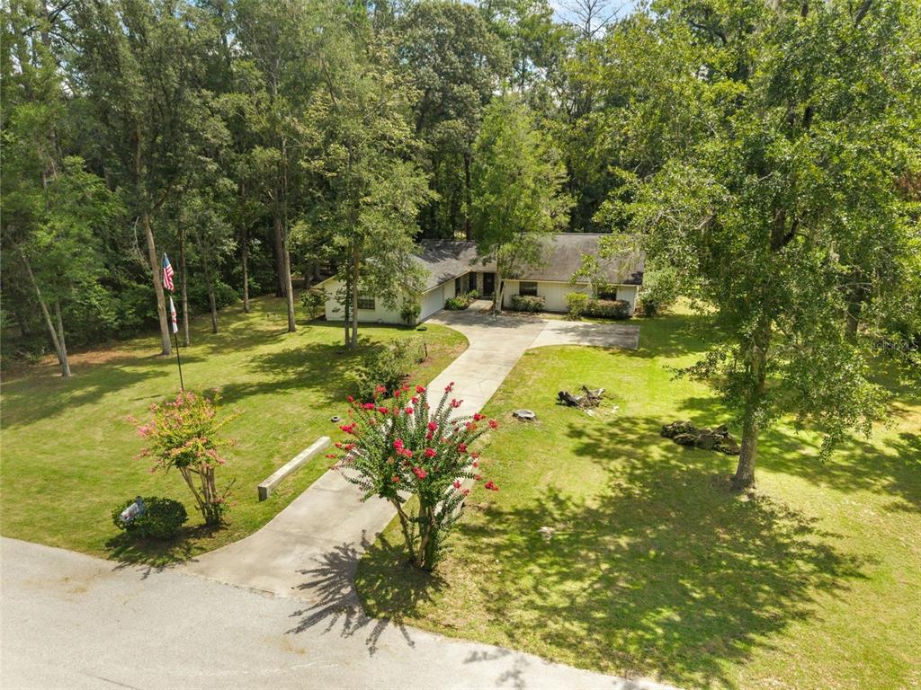 An aerial view of a single-story house with a long driveway surrounded by mature trees — 1317 SW 98TH STREET, GAINESVILLE, FL