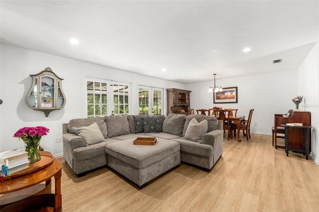 A living room with a gray sectional sofa, dining area, and light wood-look flooring — 1317 SW 98TH STREET, GAINESVILLE, FL