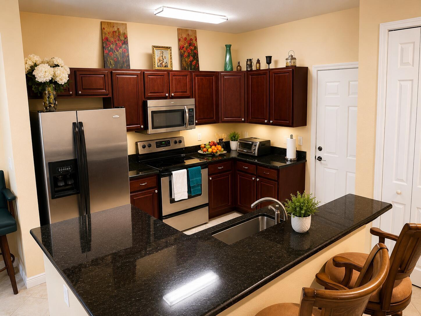 A kitchen features dark wood cabinets, black granite countertops, stainless steel appliances, and a breakfast bar — 4206 Emerald Vista, Lake Worth FL 33461, LAKE WORTH, FL