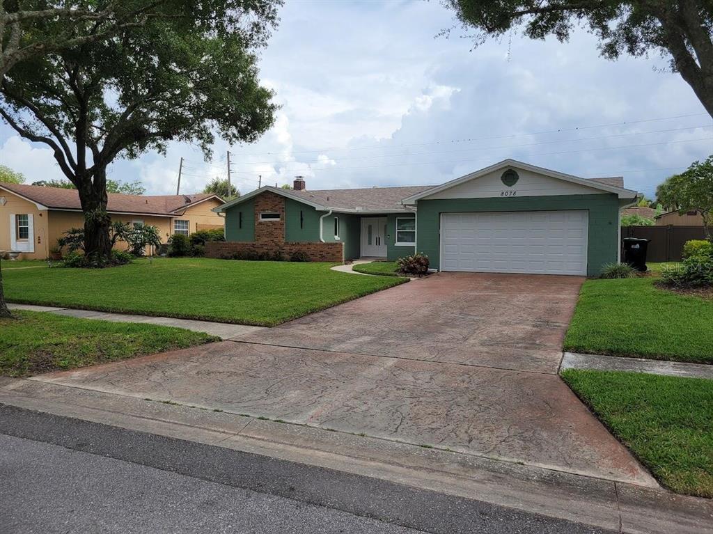 A green single-story house with a two-car garage and a stamped concrete driveway — 8078 NICKLAUS DRIVE, ORLANDO, FL