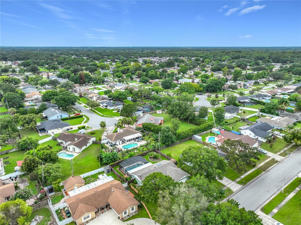 An aerial view shows a suburban neighborhood with single-family homes, swimming pools, and green lawns — 8078 NICKLAUS DRIVE, ORLANDO, FL