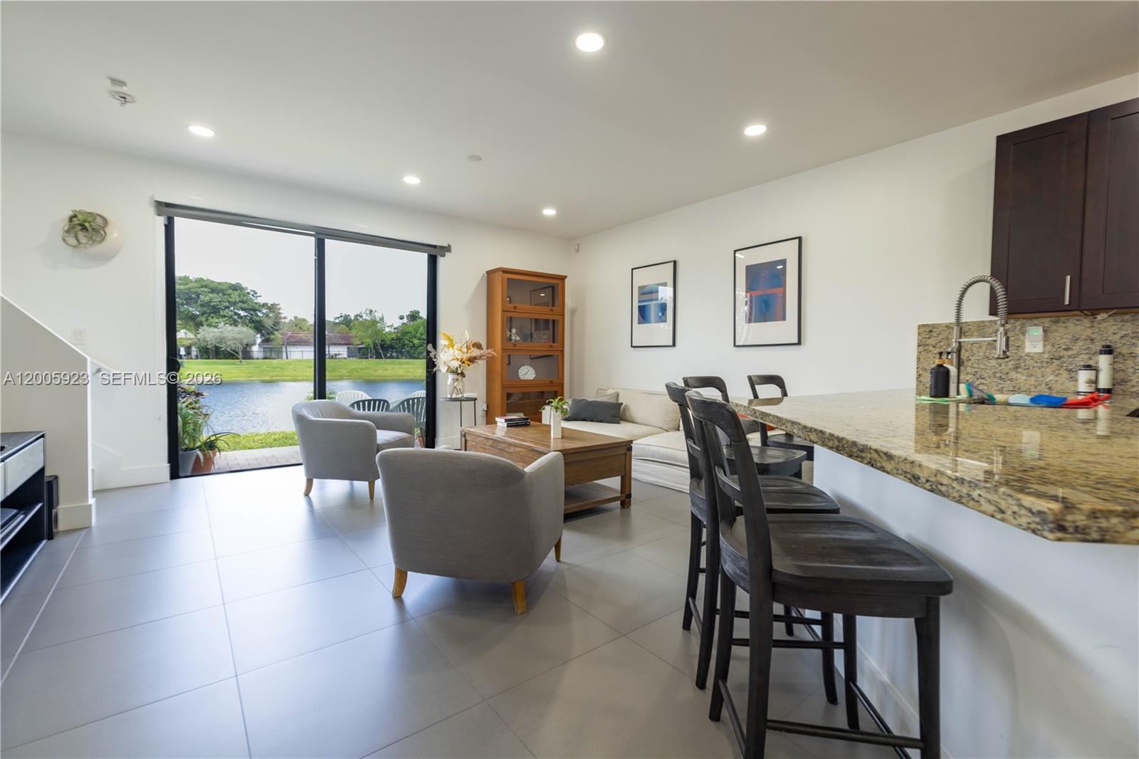 A living room and kitchen area with tile floors, bar seating, and a lake view — 345 NE 194th Ln, Miami FL 33179, MIAMI, FL