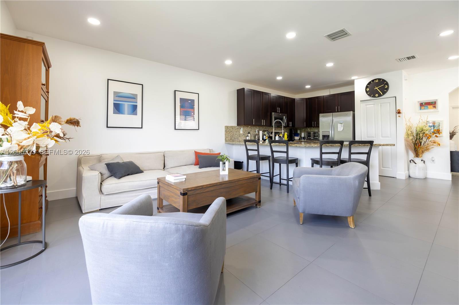 A living room with a beige sofa, two gray armchairs, and an open kitchen area — 345 NE 194th Ln, Miami FL 33179, MIAMI, FL