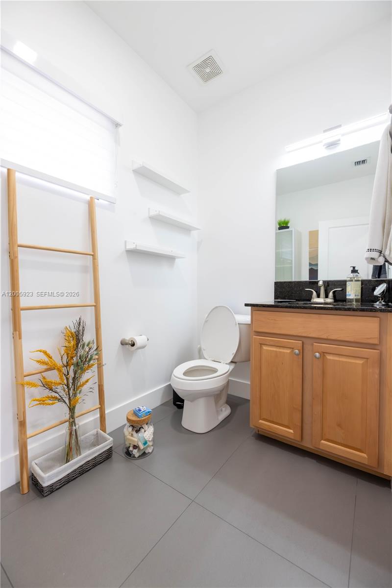 A bathroom features a wooden vanity, a toilet, floating shelves, and a decorative wooden ladder — 345 NE 194th Ln, Miami FL 33179, MIAMI, FL