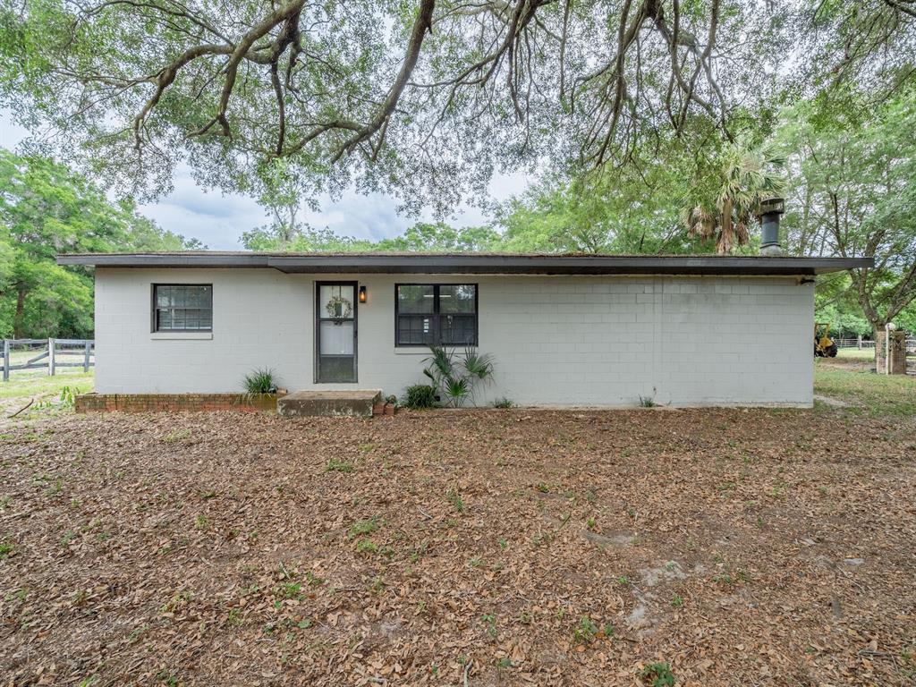 A single-story gray concrete block house with a flat roof sits on a dirt lot — 4521 NE 28TH AVENUE, OCALA, FL