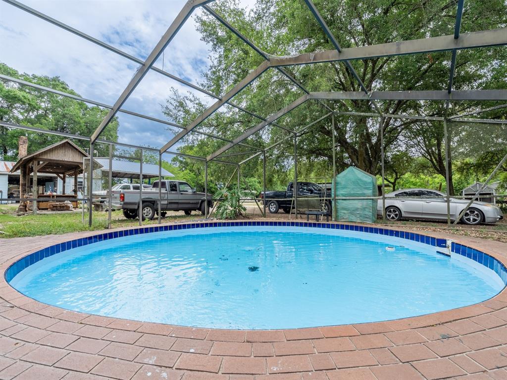A round swimming pool is enclosed by a screened lanai with a brick paver deck — 4521 NE 28TH AVENUE, OCALA, FL