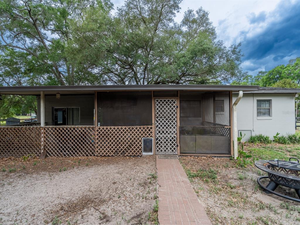 A screened-in porch with lattice skirting and a brick walkway sits beside a house exterior — 4521 NE 28TH AVENUE, OCALA, FL
