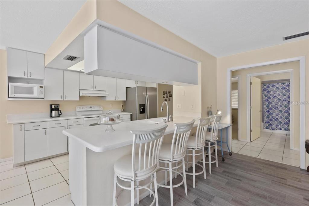 A kitchen with white cabinets, a breakfast bar with four chairs, and stainless steel appliances — 1895 BUCCANEER CIRCLE, SARASOTA, FL
