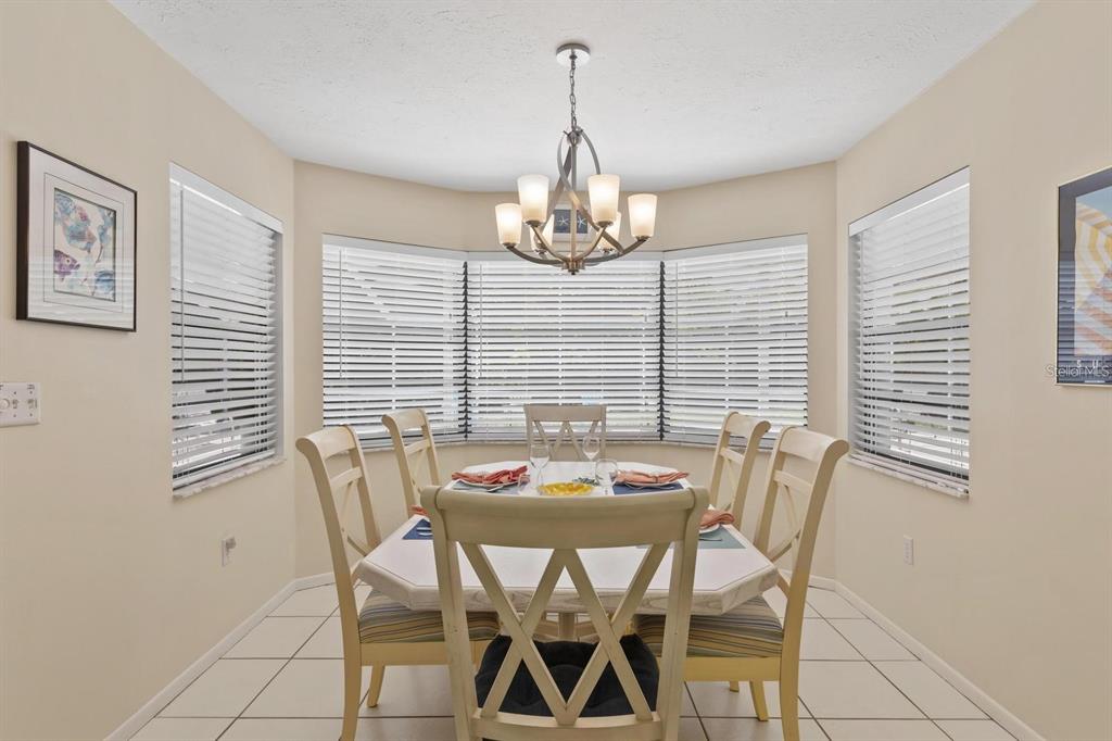 A dining area features a white table with four chairs under a chandelier near windows — 1895 BUCCANEER CIRCLE, SARASOTA, FL