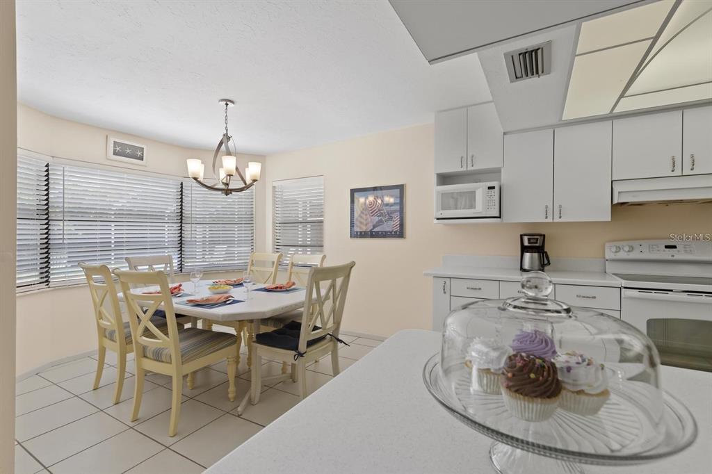 A kitchen and dining area with white cabinets, tile flooring, and a cupcake display — 1895 BUCCANEER CIRCLE, SARASOTA, FL