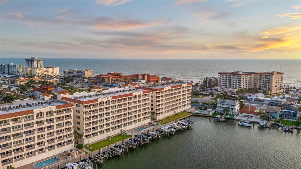 An aerial view shows multi-story waterfront condominiums with boat slips along a canal at sunset — 17717 GULF BOULEVARD UNIT 604, REDINGTON SHORES, FL
