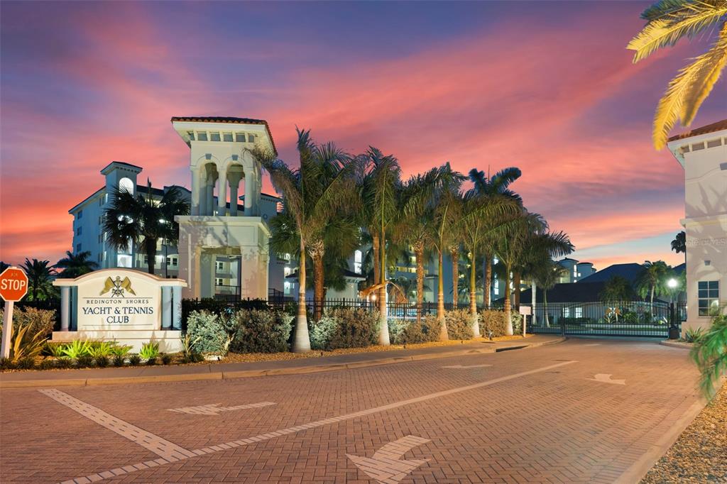 The entrance to the Redington Shores Yacht & Tennis Club features a paved driveway at sunset — 17717 GULF BOULEVARD UNIT 604, REDINGTON SHORES, FL