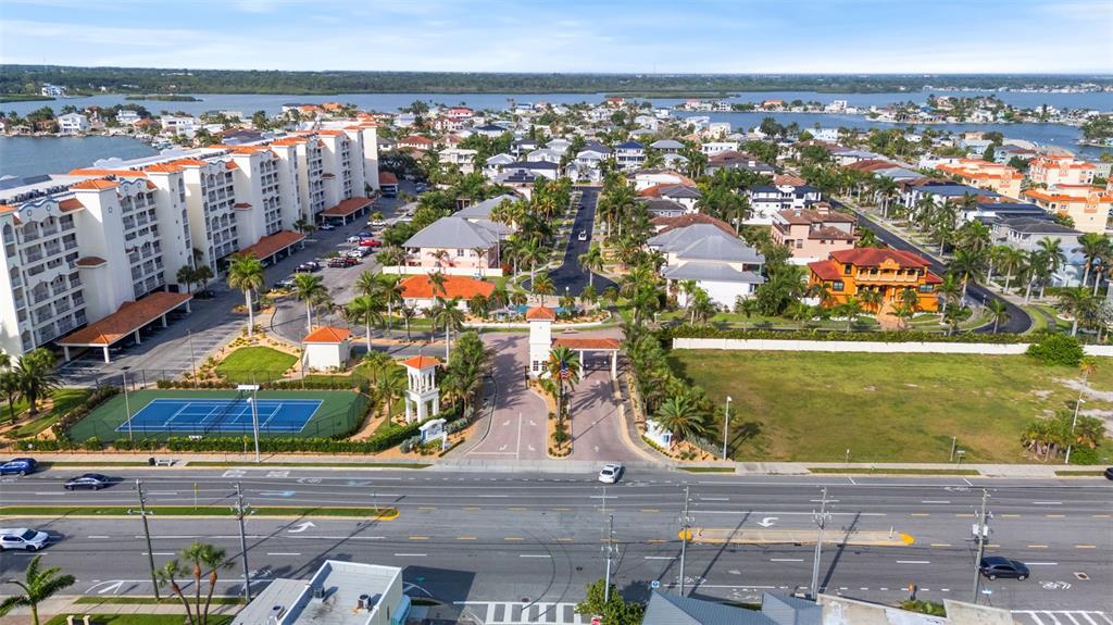 An aerial view shows a gated residential community with a tennis court and nearby waterfront — 17717 GULF BOULEVARD UNIT 604, REDINGTON SHORES, FL