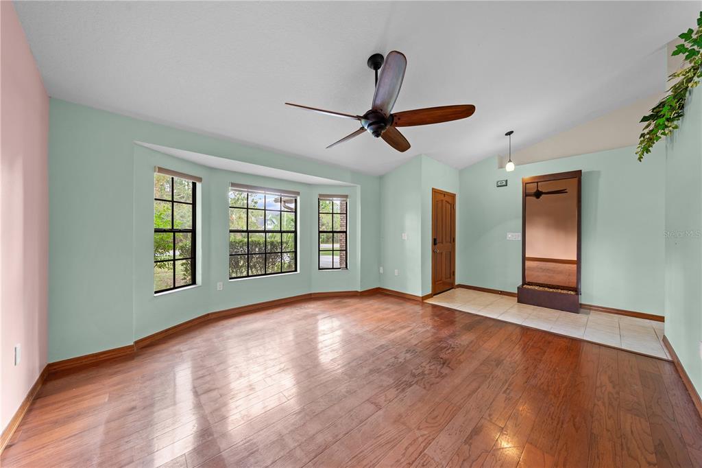 A room with light green walls, hardwood floors, a bay window, and a ceiling fan — 1860 MUSTANG COURT, ST CLOUD, FL